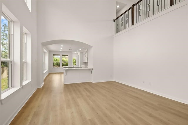 122 Canary Island Cir, Montgomery, TX 77316 - unfurnished living room with a high ceiling, light wood-style floors, arched walkways, and recessed lighting