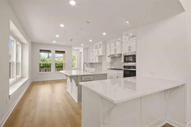 122 Canary Island Cir, Montgomery, TX 77316 - kitchen with wall oven, stainless steel microwave, recessed lighting, gas stovetop, and a kitchen island with sink