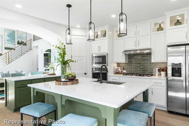 122 Canary Island Cir, Montgomery, TX 77316 - kitchen featuring stainless steel appliances, light wood-type flooring, light countertops, a breakfast bar area, and under cabinet range hood
