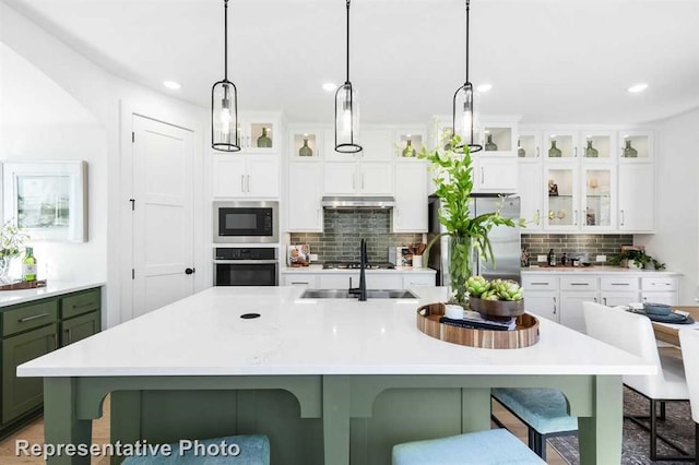 122 Canary Island Cir, Montgomery, TX 77316 - kitchen featuring stainless steel appliances, under cabinet range hood, decorative backsplash, light countertops, and recessed lighting