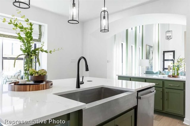 122 Canary Island Cir, Montgomery, TX 77316 - kitchen with green cabinetry, stainless steel dishwasher, light stone counters, pendant lighting, and light wood-style floors