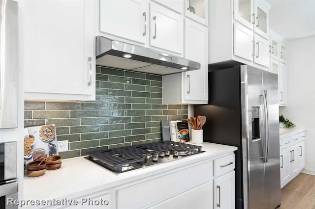 122 Canary Island Cir, Montgomery, TX 77316 - kitchen featuring under cabinet range hood, appliances with stainless steel finishes, light countertops, white cabinets, and decorative backsplash