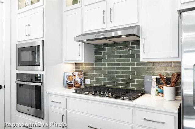 122 Canary Island Cir, Montgomery, TX 77316 - kitchen with appliances with stainless steel finishes, ventilation hood, white cabinets, decorative backsplash, and light countertops