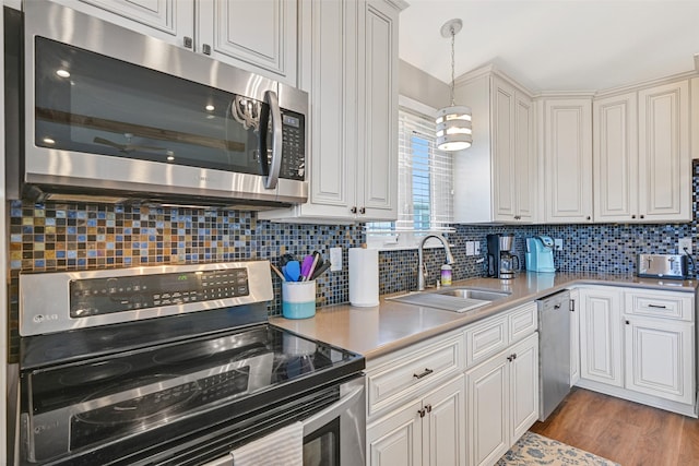16605 Flounder Way, Jamaica Beach, TX 77554 - kitchen with stainless steel appliances, backsplash, light countertops, a sink, and decorative light fixtures