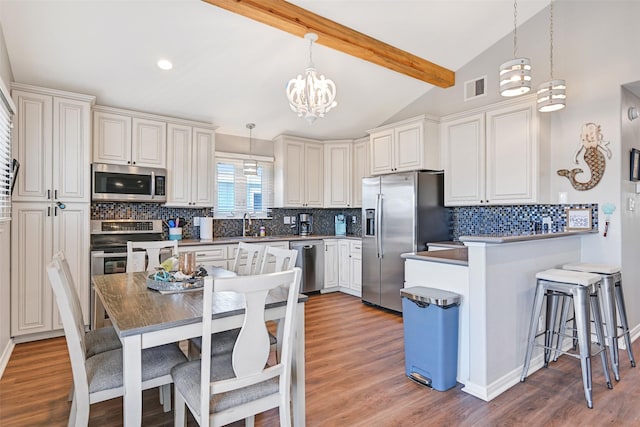 16605 Flounder Way, Jamaica Beach, TX 77554 - kitchen with an inviting chandelier, visible vents, a peninsula, appliances with stainless steel finishes, and a breakfast bar area