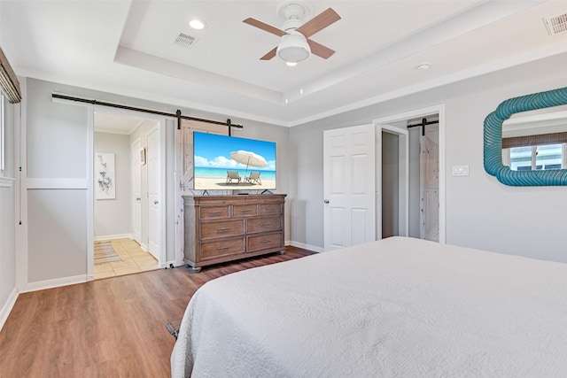 16605 Flounder Way, Jamaica Beach, TX 77554 - bedroom featuring a barn door, wood finished floors, visible vents, and baseboards