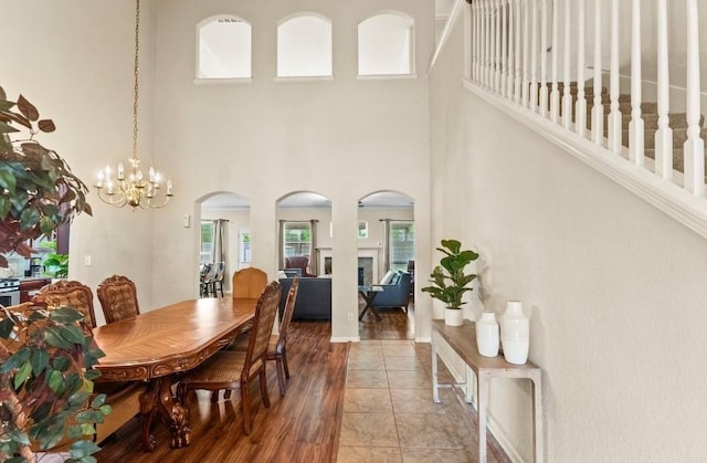 dining room featuring light wood finished floors, a high ceiling, arched walkways, and a notable chandelier