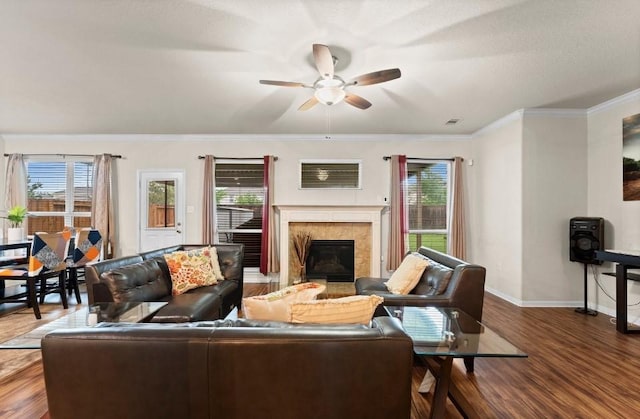 living area with a tiled fireplace, a ceiling fan, baseboards, and a wealth of natural light