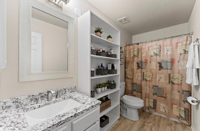 full bathroom featuring wood finished floors, vanity, curtained shower, toilet, and visible vents