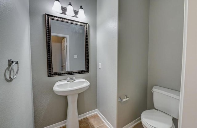 half bath with toilet, tile patterned flooring, and baseboards