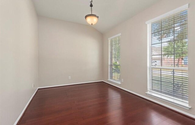 unfurnished room featuring lofted ceiling, baseboards, and dark wood-style flooring