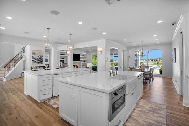 16059 Walden Rd, Conroe, TX 77356 - kitchen with an inviting chandelier, a sink, white cabinetry, stainless steel microwave, and a spacious island