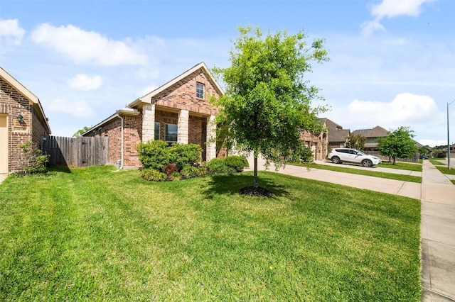 view of front of house with a front lawn, brick siding, and fence