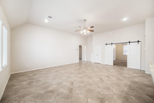 unfurnished bedroom with a barn door, vaulted ceiling, visible vents, arched walkways, and baseboards