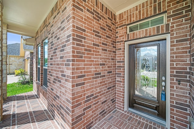doorway to property with brick siding and covered porch