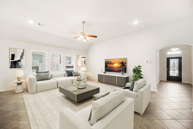 living area featuring arched walkways, lofted ceiling, a wealth of natural light, and visible vents