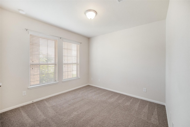 carpeted spare room featuring baseboards