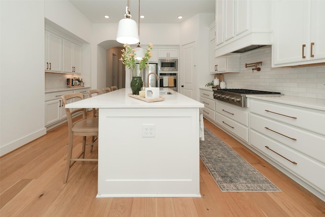 14924 Scarlet Branch Dr, Conroe, TX 77302 - kitchen with a kitchen breakfast bar, stainless steel appliances, premium range hood, backsplash, and white cabinetry