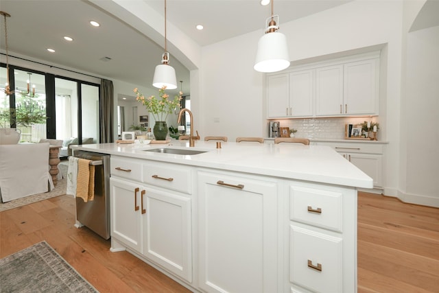 14924 Scarlet Branch Dr, Conroe, TX 77302 - kitchen featuring dishwasher, tasteful backsplash, a sink, and light wood-style flooring