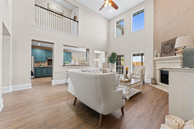 14911 Hurst Point Ln, Houston, TX 77049 - living room with ceiling fan, light wood-style floors, a fireplace with raised hearth, baseboards, and a high ceiling