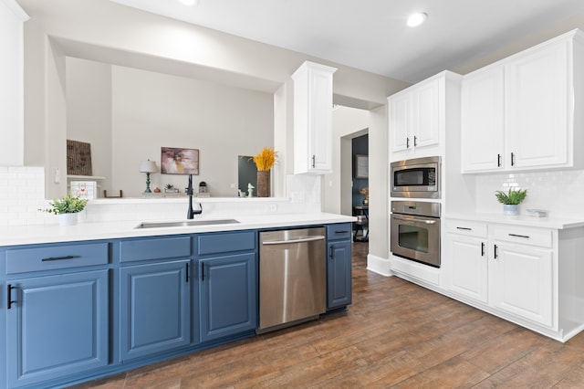14911 Hurst Point Ln, Houston, TX 77049 - kitchen featuring stainless steel appliances, blue cabinetry, a sink, tasteful backsplash, and dark wood-style flooring