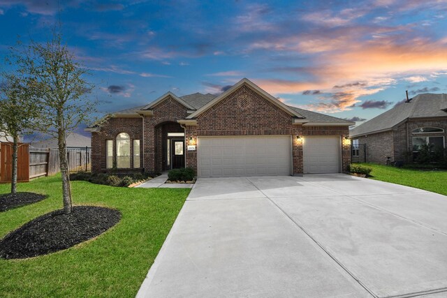view of front of home with fence, a front lawn, an attached garage, driveway, and brick siding