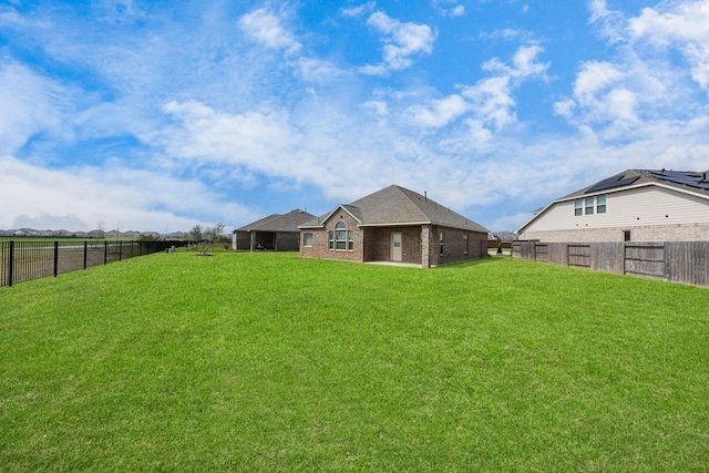 rear view of property featuring a fenced backyard and a yard