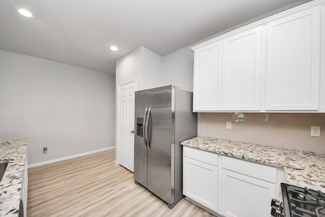 kitchen with light wood-type flooring, white cabinetry, backsplash, and appliances with stainless steel finishes
