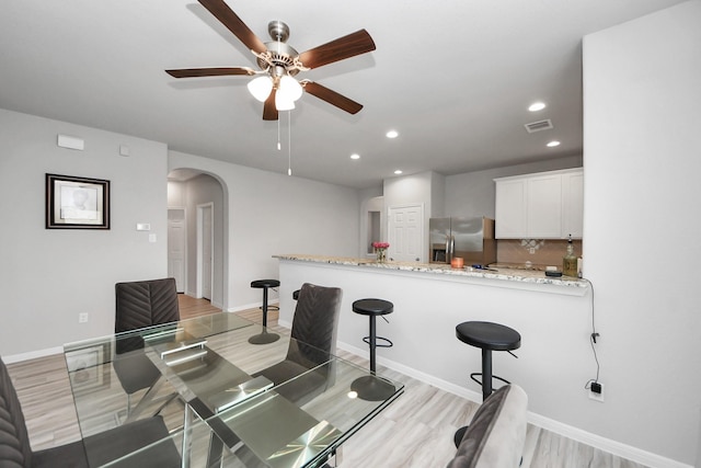 kitchen with white cabinets, visible vents, arched walkways, stainless steel refrigerator with ice dispenser, and ceiling fan