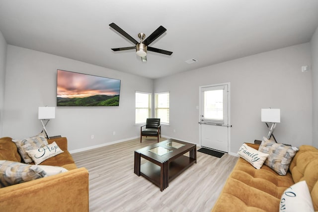 living room featuring baseboards, a ceiling fan, visible vents, and light wood-type flooring