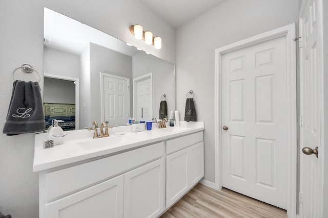 bathroom with double vanity, connected bathroom, wood finished floors, and a sink