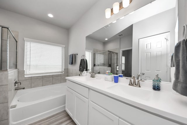 bathroom with visible vents, a garden tub, a stall shower, and a sink