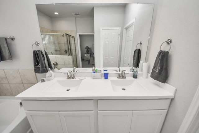 bathroom with double vanity, a shower stall, visible vents, and a sink