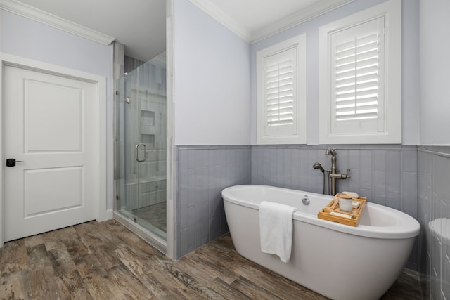 full bath with wood finished floors, a shower stall, ornamental molding, and a freestanding bath