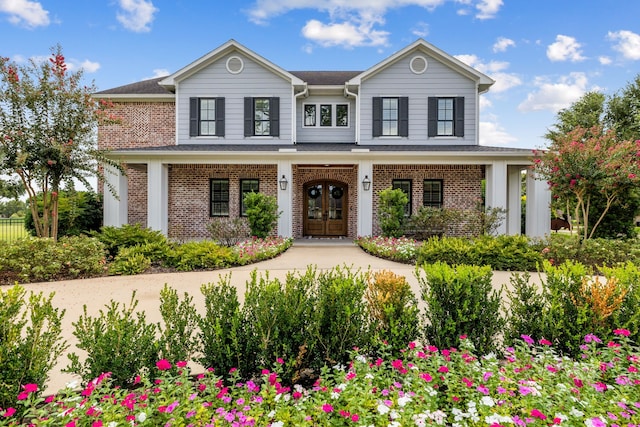 traditional home featuring brick siding, a porch, and french doors
