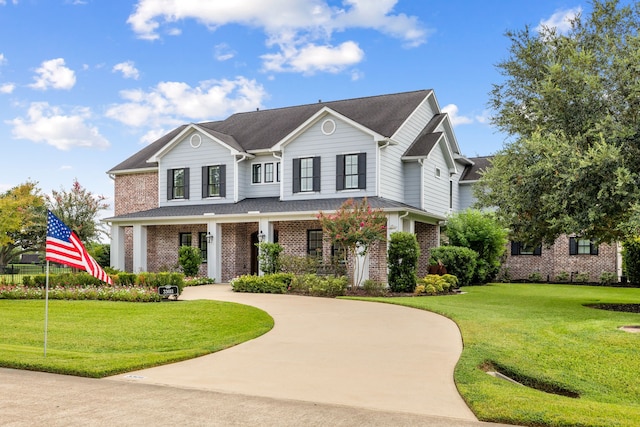 view of front of property featuring brick siding, covered porch, and a front yard