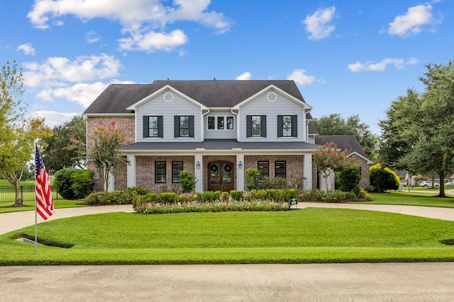 view of front of house with brick siding, a front yard, covered porch, and curved driveway