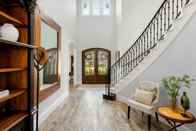 entrance foyer featuring stairway, wood finished floors, french doors, arched walkways, and baseboards
