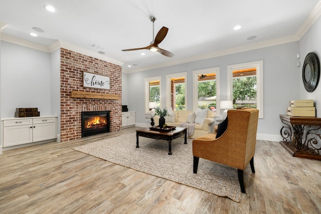 living room featuring light wood finished floors, a ceiling fan, crown molding, baseboards, and a fireplace