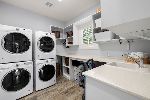 clothes washing area with a sink, visible vents, stacked washing maching and dryer, washer and dryer, and laundry area