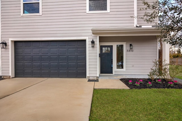 entrance to property with a lawn, an attached garage, and driveway