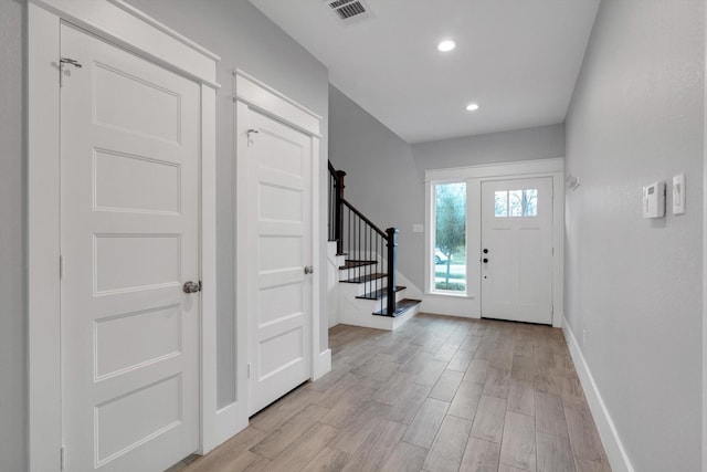 entrance foyer with stairway, light wood-style floors, baseboards, visible vents, and recessed lighting