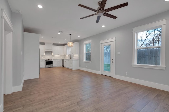 unfurnished living room featuring light wood-style floors, a wealth of natural light, and a sink