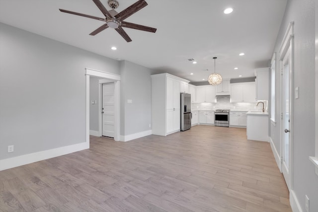 unfurnished living room with ceiling fan, baseboards, light wood-type flooring, and recessed lighting
