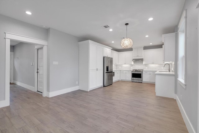 kitchen featuring a sink, stainless steel appliances, light countertops, backsplash, and visible vents