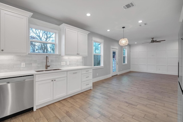 kitchen with white cabinets, stainless steel dishwasher, a sink, visible vents, and light countertops