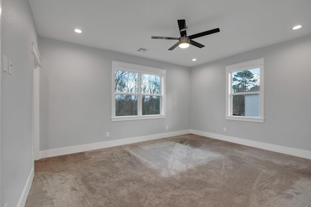 carpeted empty room featuring a ceiling fan, baseboards, a healthy amount of sunlight, and visible vents
