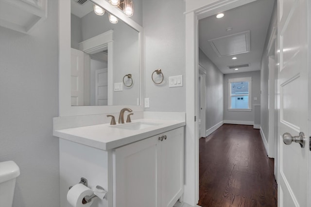half bath with wood finished floors, visible vents, toilet, and vanity