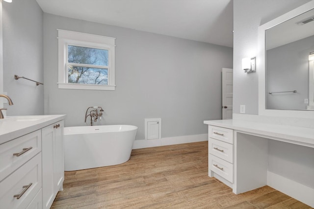 full bathroom with a freestanding tub, wood finished floors, visible vents, and vanity