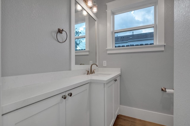 bathroom featuring baseboards, a textured wall, vanity, and wood finished floors